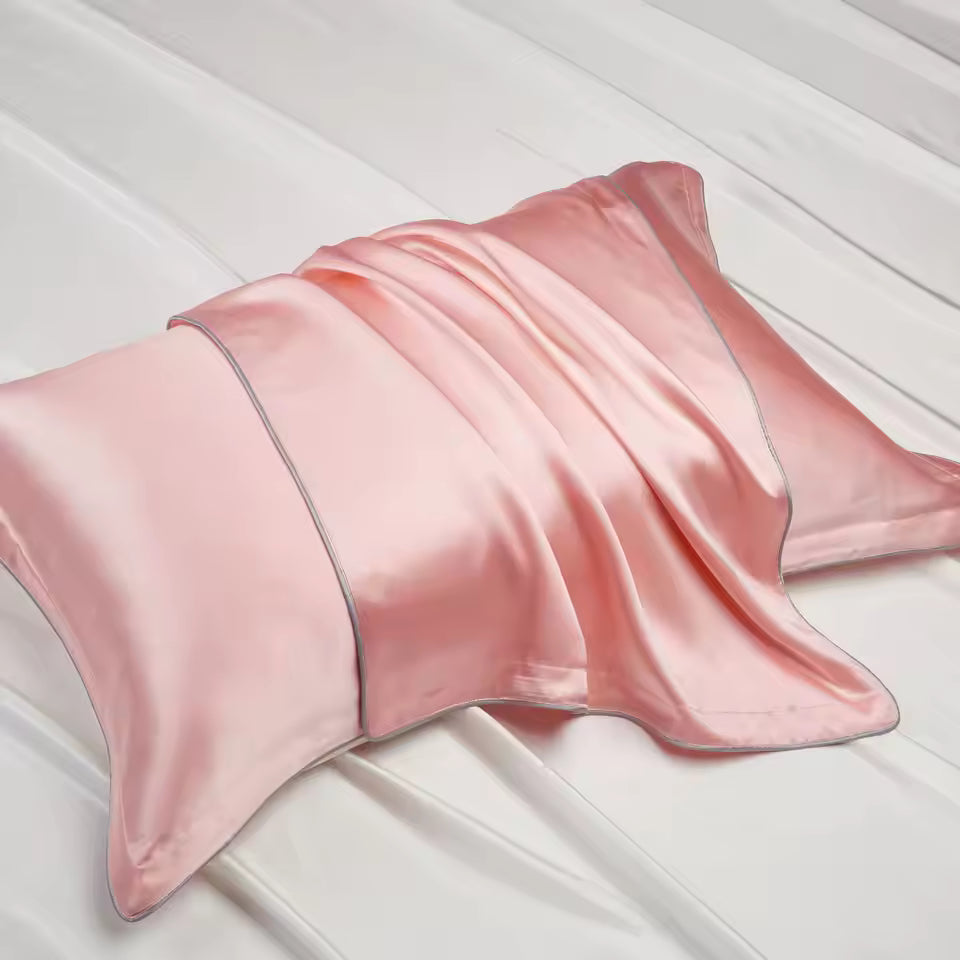 A soft pink silk pillowcase draped smoothly over a pillow on white fabric background.