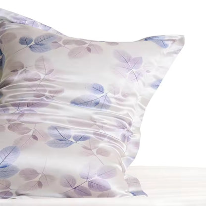 Close-up shot of a white silk pillowcase with a purple leaf pattern, highlighting the smooth texture and slight sheen of the fabric.