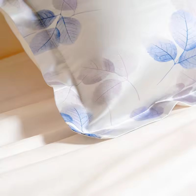 Extreme close-up shot of the corner flange detailing on a silk pillowcase featuring a purple and blue leaf pattern.