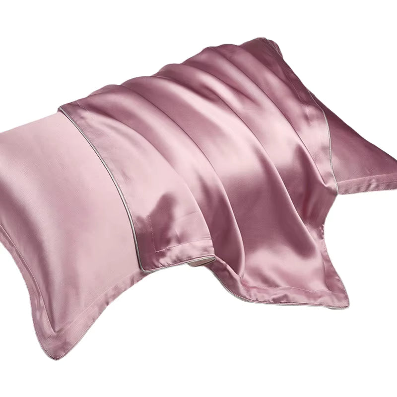 A smooth, dusky pink silk pillowcase draped elegantly over a pillow against a plain background.